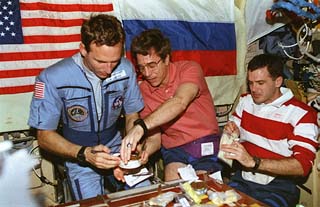 Mission Specialists Jerry Linenger, John Blaha and Jeff Wisoff gather around the wardroom table, sampling Russian food . 